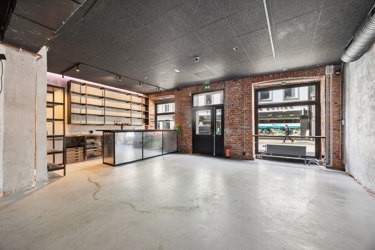 Åpent lokale med store vinduer mot gaten og eksisterende barområde – godt egnet for et nytt restaurant- eller cafékonsept.