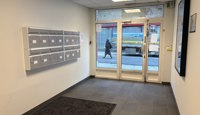 Inngangsparti med heis og infoskjerm for leietakeroversikt.