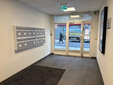 Inngangsparti med heis og infoskjerm for leietakeroversikt.