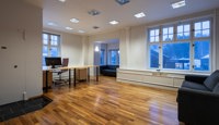 Romslig kontor med plass til både arbeidsstasjoner og sitteområde, egnet for flere arbeidsplasser eller kombinasjonsbruk