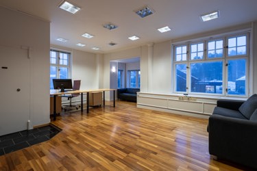 Romslig kontor med plass til både arbeidsstasjoner og sitteområde, egnet for flere arbeidsplasser eller kombinasjonsbruk