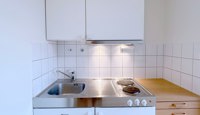 Minikjøkken med to kokeplater, kjøleskap med liten frysedel.