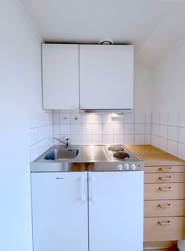 Minikjøkken med to kokeplater, kjøleskap med liten frysedel.
